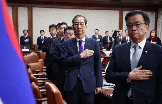 한덕수 대통령 권한대행(오른쪽 두 번째)이 17일 서울 종로구 정부서울청사에서 열린 국무회의에서 국기에 경례하고 있다.연합뉴스.