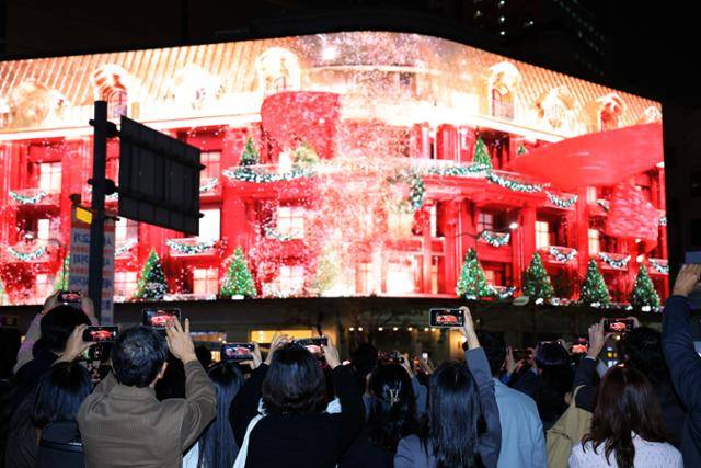 11월 1일 서울 중구 신세계백화점 본점 앞에서 시민들이 외벽에 설치된 LED 사이니지 신세계스퀘어에서 펼쳐진 미디어 파사드를 휴대전화로 촬영하고 있다. 뉴스1