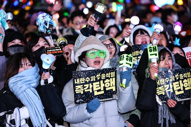Protesters cheer with light sticks and placards at a rally, after the impeachment of President Yoon Suk Yeol was passed in parliament near the National Assembly in western Seoul on Dec. 14. [JOONGANG ILBO]