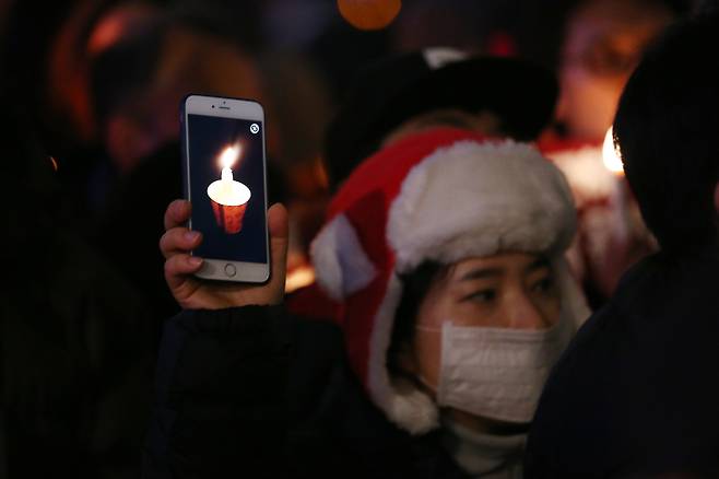 A protester uses a candlelight app on a smartphone to protest for the impeachment of former President Park Geun-hye in central Seoul on Nov. 26, 2016. [JOONGANG ILBO]