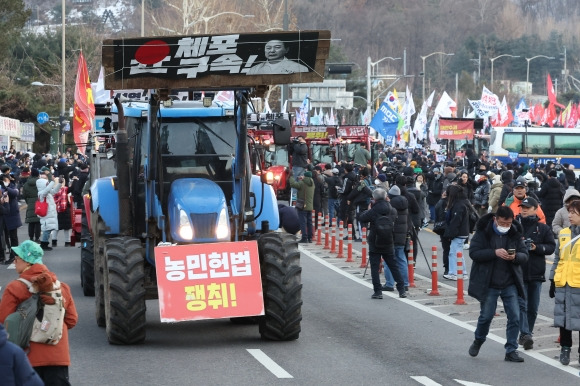 경찰 버스 지나 행진하는 트랙터들 - 22일 오후 서울 서초구 남태령에서 열린 ‘윤석열 대통령 체포·구속 농민 행진 보장 촉구 시민대회’에서 트랙터와 시민들이 경찰 버스를 지나 한남동 대통령 관저 방향으로 행진하고 있다.  연합뉴스