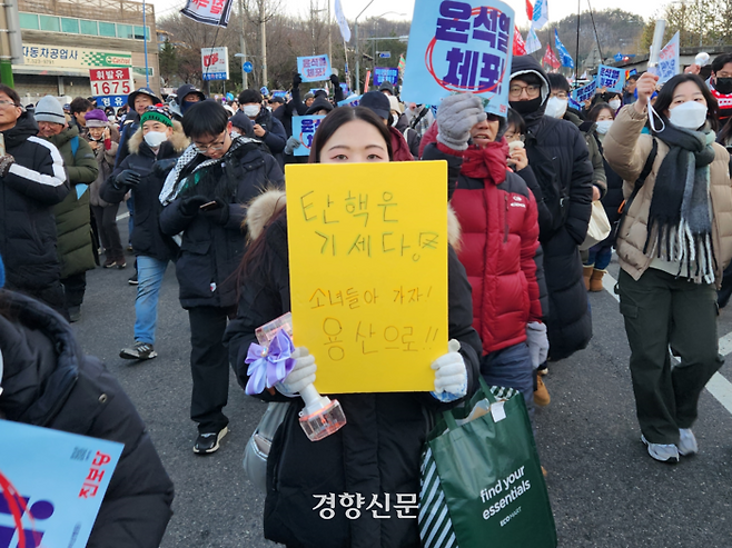 회사원 강채원씨(33)가 22일 서울 남태령역 인근에서 열린 ‘남태령 대첩’서 손팻말을 들고 시민들과 행진하고 있다. 오동욱 기자