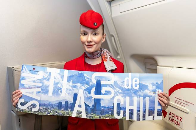 터키항공 승무원이 칠레 산티아고 운항 기념 포스터를 들고 기념사진을 촬영하고 있다. [터키항공 제공]