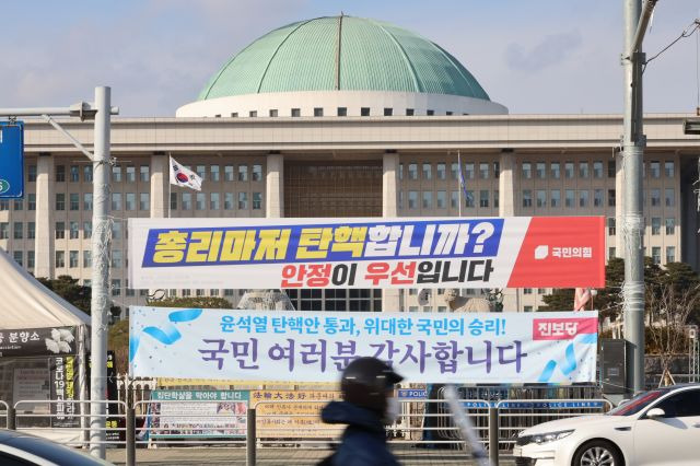 더불어민주당이 한덕수 대통령 권한대행 국무총리에 대한 탄핵소추안을 만장일치 당론으로 채택한 가운데 25일 서울 여의도 국회의사당 정문에 "총리마저 탄핵합니까? 안정이 우선입니다"라고 적힌 국민의힘의 현수막이 걸려 있다. 연합뉴스