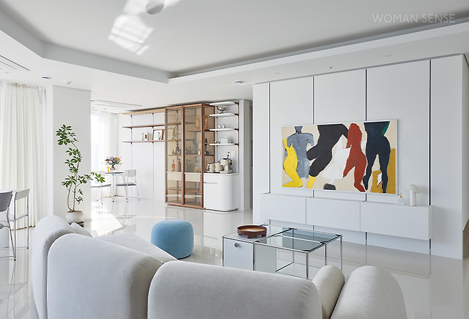 액자와 같은 프레임 디자인과 맞춤형 베젤로 공간을 갤러리로 만들어주는 아트 TV 삼성 더 프레임. TV를 끄는 순간 예술 작품을 띄워주는 아트 모드가 있어 거실에 대형 액자를 들인 것 같다. 아트 모드에서는 작품의 섬세한 질감까지 느낄 수 있다. 통창으로 빛이 많이 들어오는 집이라 화면 반사가 심했는데, 빛 반사가 적은 매트 디스플레이를 적용한 삼성 더 프레임을 들인 후 편안하게 영화나 유튜브 모니터링을 할 수 있어 좋다. 삼성전자 제품. 벽걸이형 화이트 TV장과 트로피 등을 전시할 수 있는 장식장은 더틀에서 맞춤 제작했다. 밤에 조명이 켜지면 분위기가 근사해지고, 이동식 선반이 있는 모듈 가구라 형태 변형이 자유롭다. 식물의시간에서 수형을 아름답게 만든 홍콩야자는 넓은 공간에 리듬감을 선사한다.