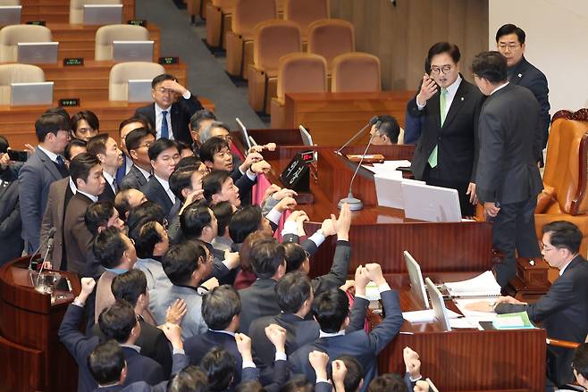 우원식 국회의장이 지난 27일 오후 국회 본회의에서 한덕수 국무총리 탄핵소추안 가결 의결 정족수(재적 의원 과반 찬성)에 대해 설명하자, 권성동 국민의힘 당대표 권한대행 겸 원내대표가 의장석에 올라가 항의하고 있다. [연합]