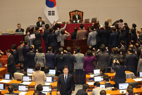 지난 27일 오후 우원식 국회의장이 국회 본회의에서 한덕수 국무총리 탄핵소추안 가결 요건을 '재적 과반'으로 정하자 국민의힘 의원들이 항의하고 있는 가운데 투표를 마친 더불어민주당 이재명 대표가 미소를 머금은 채 자리로 향하고 있다.  [연합뉴스]