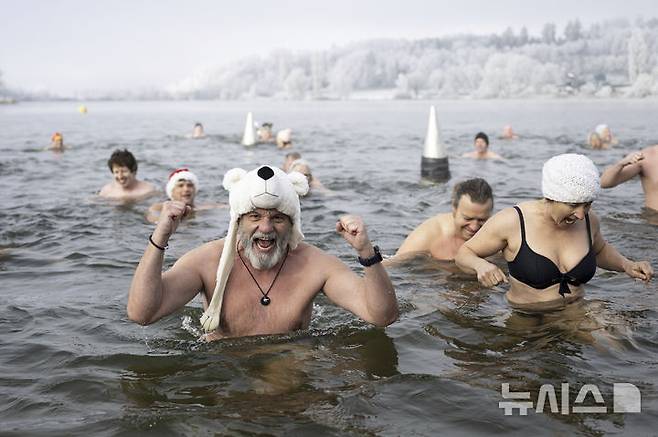 [모제도르프=AP/뉴시스] 지난해 12월 31일(현지시각) 스위스 모제도르프의 모제 호수에서 전통 새해맞이 전야제가 열려 참가자들이 찬물에 몸을 담그며 새해를 맞고 있다. 2025.01.01.