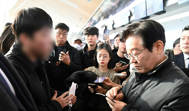 이재명 더불어민주당 대표가 지난 31일 오전 전남 무안군 무안국제공항 터미널을 찾아 제주항공 여객기 사고 희생자 유가족을 위로하며 요구사항을 수첩에 적고 있다. 뉴스1