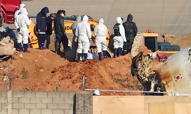 3일 오전 전남 무안군 무안국제공항 제주항공 여객기 참사 현장에서 항공철도사고조사위원회 및 국과수 관계자 등이 방위각시설(로컬라이저)에 파묻힌 엔진을 살펴보고 있다. [연합]