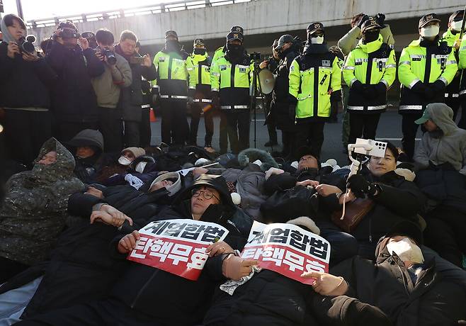 윤석열 대통령에 대한 체포영장 발부 사흘째인 1월2일 서울 용산구 한남동 대통령 관저 정문 앞 도로에 누워있는 지지자들을 경찰들이 해산시키고 있다. ⓒ 연합뉴스