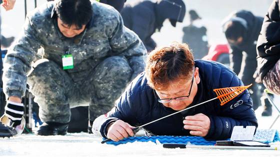 강원도 평창군 진부면 오대천 일원에서 열리는 평창송어축제장에서 방문객이 얼음 낚시를 하는 모습. [사진 평창송어축제]