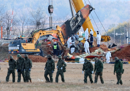 제주항공 여객기 참사 7일째인 4일 오후 무안국제공항 사고 현장에서 수색 작업을 벌이는 특전사 대원들 뒤로 방위각시설(로컬라이저)에서 두 번째 엔진 인양 작업이 진행되고 있다. 연합뉴스