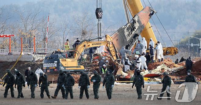 제주항공 여객기 참사 7일째인 4일 오후 전남 무안국제공항 참사 현장에서 특전사 대원들의 수색 작업 뒤로 방위각시설(로컬라이저)에서 엔진 인양 작업이 진행되고있다. 2025.1.4/뉴스1 ⓒ News1 김진환 기자