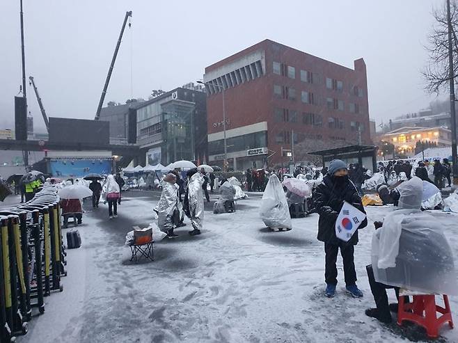 용산구 루터 교회 앞 폭설 속에서 삼삼오오 모여 의견을 나누는 반대집회 참가자들 모습. 사진=최승한 기자