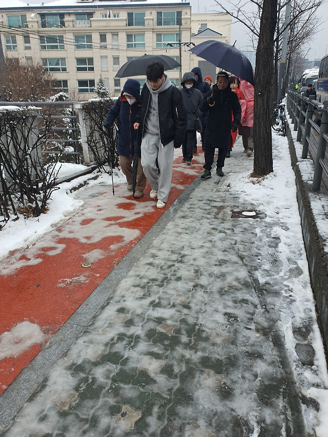 5일 오후 서울 용산구 한남동 대통령 관저 일대에서 만난 정모씨(24)가 거동이 불편한 고령의 여성을 부축이고 있다. 사진=최승한 기자