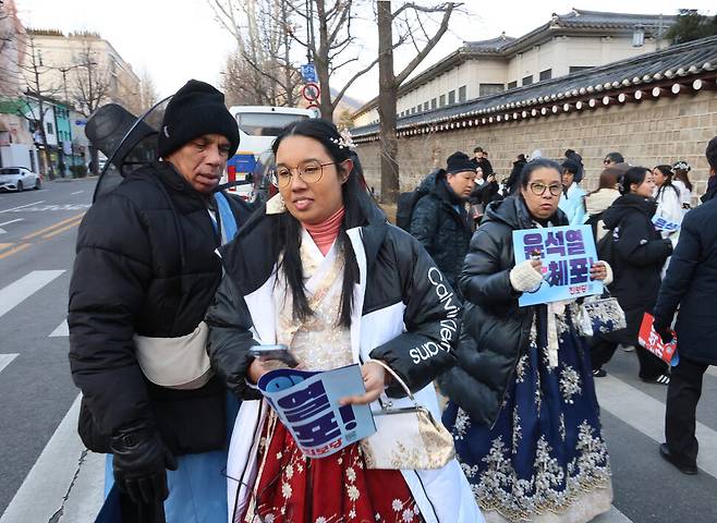 한복을 입은 외국인 관광객들이 경복궁을 관람하고 나오다 시민들이 나눠준 손팻말을 들어보이고 있다.