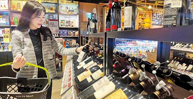 서울 신천동 롯데마트 월드타워점의 주류 매장에서 한 소비자가 와인을 담고 있다. /롯데마트 제공