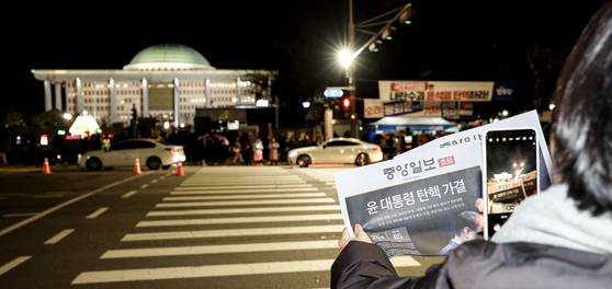 윤석열 대통령 탄핵안이 국회에서 가결된 지난달 14일, 여의도 국회의사당을 배경으로 중앙일보 호외를 들고 '인증샷'을 찍는 시민. 김경록 기자