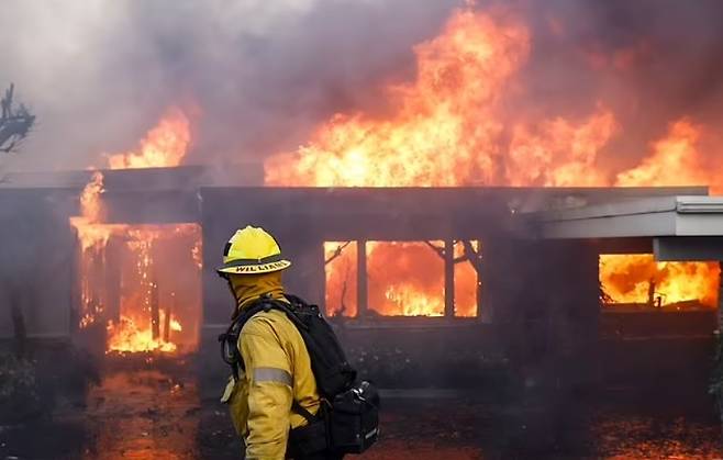 불타는 집 앞에 선 로스앤젤레스 카운티 소방관 [EPA]