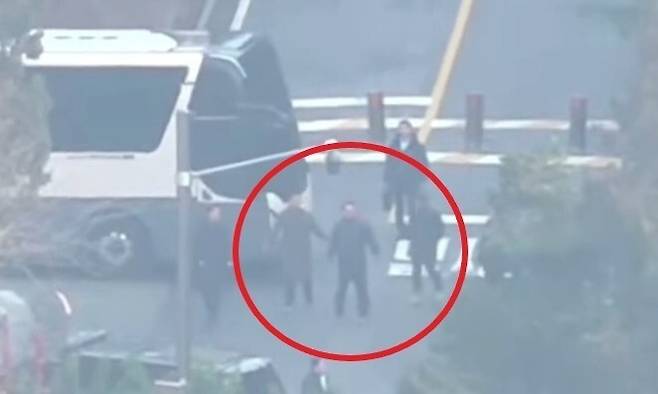 윤석열 대통령으로 추정되는 남성(붉은 원)과 그 뒤에 가방을 든 경호관의 모습이 보인다. [오마이TV 갈무리]