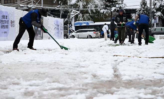서울 등 중부 지역에 많은 눈이 내린 27일 오전 서울시청 광장에서 서울시 관계자들이 눈을 치우고 있다. 이상섭 기자
