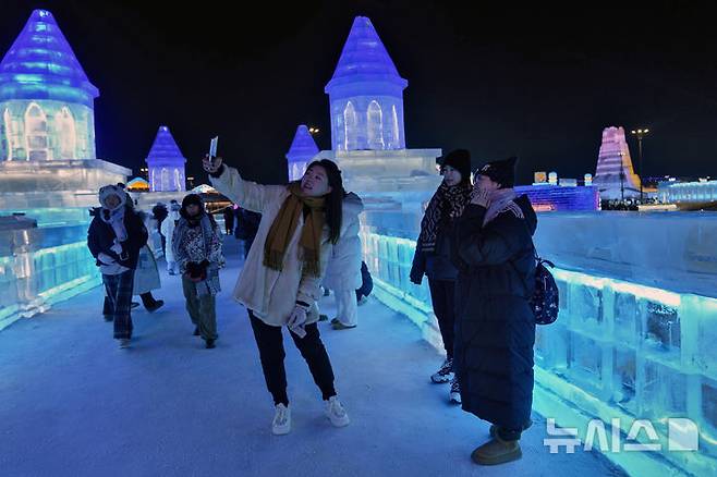 Visitors take selfie with the illuminated ice structures at the Harbin Ice and Snow World in Harbin, China's Heilongjiang province on Sunday, Jan. 5, 2025. (AP Photo/Andy Wong)