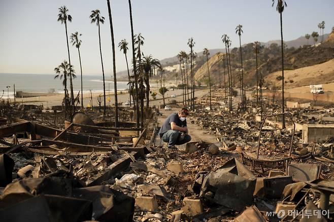 케빈 마샬이 11일 팰리세이즈 화재로 소실된 로스앤젤레스 퍼시픽 팰리세이즈의 모친 소유 저택에서 넋을 잃고 있다. 캘리포니아주 소방 당국은 12일 팰리세이즈와 이턴, 케네스, 허스트 4개 화재로 샌프란시스코 전체 넓이보다도 더 넓은 약 160㎢가 소실됐다고 밝혔다. /AP=뉴시스