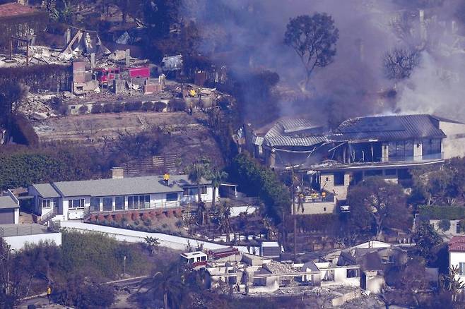미국 캘리포니아주 말리부에서 발생한 화재로 폐허로 변한 마을들을 소방대원들이 지난 9일 화재 진압을 벌이고 있다. AP 뉴시스
