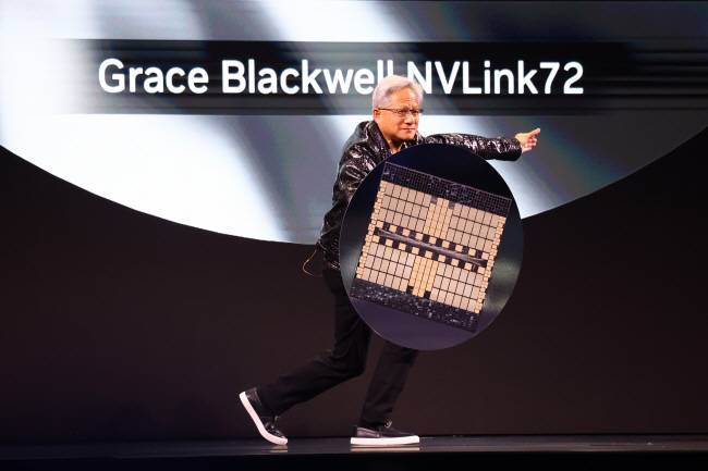 젠슨 황 엔비디아 CEO가 지난 6일 미국 라스베이거스 만달레이 컨벤션센터에서 열린 ‘소비자가전쇼(CES) 2025’ 기조연설에서 대형 컴퓨터 칩 와플을 선보이고 있다.   UPI 연합뉴스