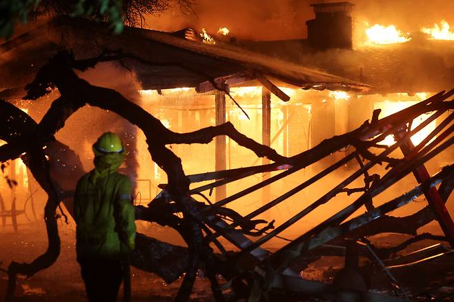 8일(현지시간) 미국 캘리포니아 패서디나에서 소방관이 이튼 파이어가 타면서 불길을 잡고 있다. [로이터]