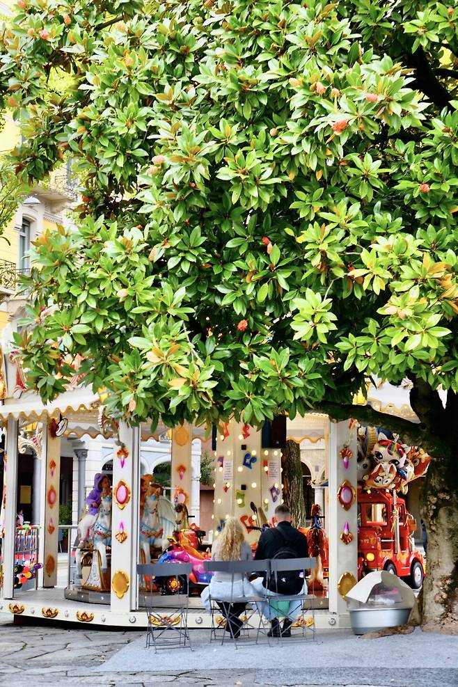 루가노 리포르마광장. 회전목마 위 딸을 지켜보는 부부