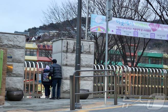 윤석열 대통령이 체포된 다음날인 16일, 서울 용산구 한남동에 위치한 한남초등학교에서 한 남성이 아이를 바래다주고 있다.2025.1.16/뉴스1 ⓒ 뉴스1 김민재 기자