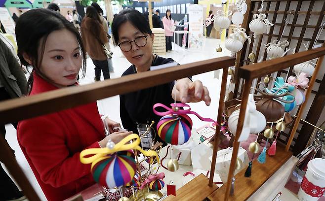 지난해 11월 22일 서울 동대문구 동대문디자인플라자에서 열린 ‘2024 대한민국 관광기념품 박람회’를 찾은 관람객이 색동복소라 풍경을 살펴보고 있다. /뉴스1