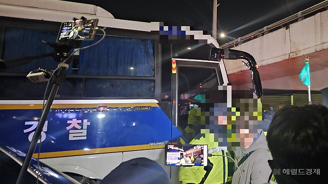 지난 15일 새벽 윤석열 대통령 체포영장 집행을 위해 경찰 버스에서 내리는 관계자들의 모습을 유튜버들이 생중계 하고 있다. 박지영 기자.