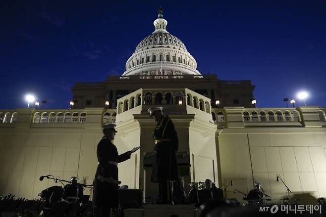 [워싱턴=AP/뉴시스] 12일(현지 시간) 미국 워싱턴 의회 의사당 서쪽에서 도널드 트럼프 대통령 당선인의 취임식을 앞두고 리허설을 진행 중인 미 해병대 군악대 '더 프레지던츠 오운'(The President's Own)'의 지휘자 라이언 놀린 중령(가운데)이 지침서를 받고 있다. 2025.01.13. /사진=민경찬