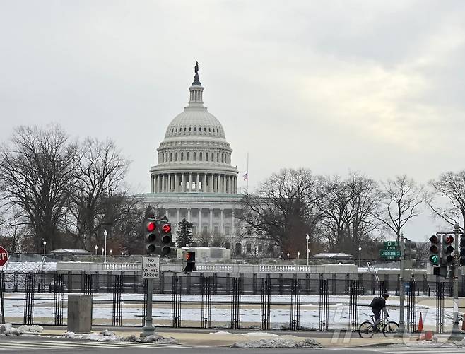 오는 20일(현지시간) 예정인 도널드 트럼프 미국 대통령의 취임식이 열릴 미 의회 의사당 건물을 둘러싼 철제 펜스 앞을 자전거를 탄 한 남성이 지나가고 있다. ⓒ News1 류정민 특파원