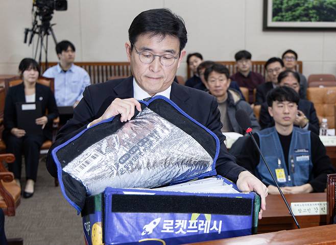 홍용준 쿠팡로지스틱스 대표가 21일 오후 서울 여의도 국회 환경노동위원회에서 열린 쿠팡 택배노동자 근로 조건 개선·대유위니아그룹 임금체불 관련 청문회에서 강득구 더불어민주당 의원 요청으로 로켓프레시백을 펼쳐보고 있다. /뉴스1