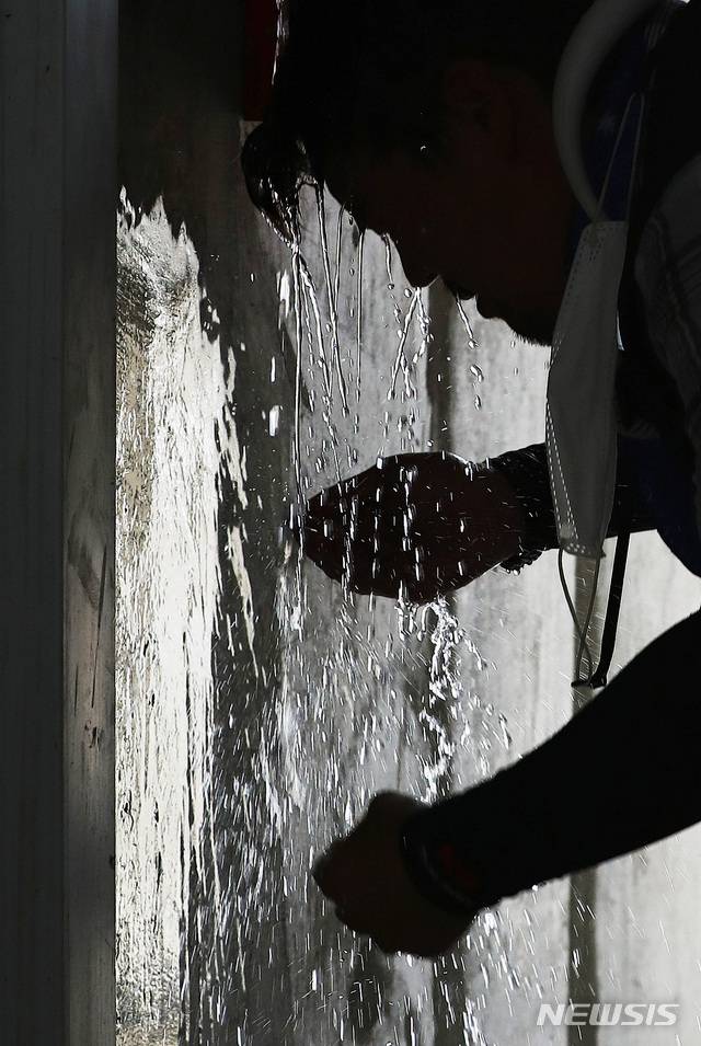 서울 용산구 건설현장에서 관계자가 찬물로 세수하며 더위를 식히고 있다. [뉴시스]