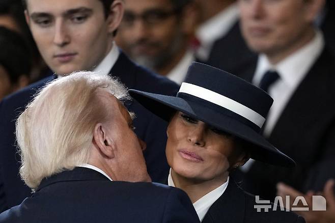 [워싱턴=AP/뉴시스] 도널드 트럼프 미국 대통령 당선인이 20일(현지 시간) 본인의 제47대 대통령 취임식이 열리는 미 연방의회 의사당 로툰다 홀에 입장해 앞서 입장한 부인 멜라니아 여사에게 입 맞추고 있다. 2025.01.21.