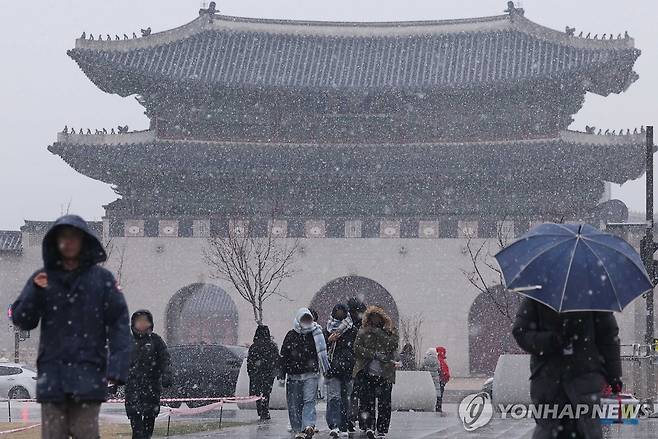 서울에 내리는 눈 (서울=연합뉴스) 김성민 기자 = 13일 오후 서울 종로구 광화문광장에서 시민들이 눈을 피해 이동하고 있다. 2025.1.13 ksm7976@yna.co.kr