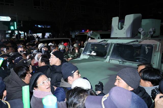 비상계엄령이 선포된 뒤 4일 새벽 국회 앞에서 군용차량을 시민들이 둘러싼 채 막아서고 있다. EPA 연합뉴스