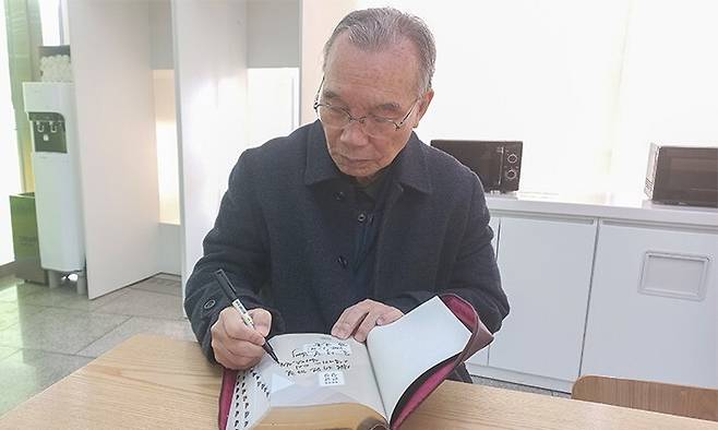 서울구치소에 수감된 내란죄 피의자 윤석열 대통령에게 보내는 성경에 사인을 하는 김진홍 목사. 두레수도원 누리집 갈무리