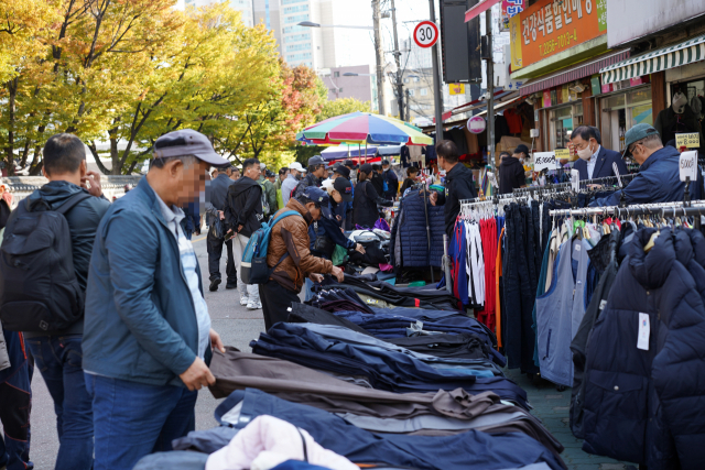 A visitor checks out pants displayed at the cloth stall in Dongmyo Flea Market in Jongno-gu, central Seoul. (Lee Si-jin/The Korea Herald)