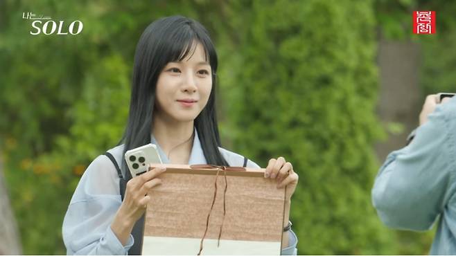 A contestant on  "I'm Solo" shows her name written on a scroll to the other person. (SBS)
