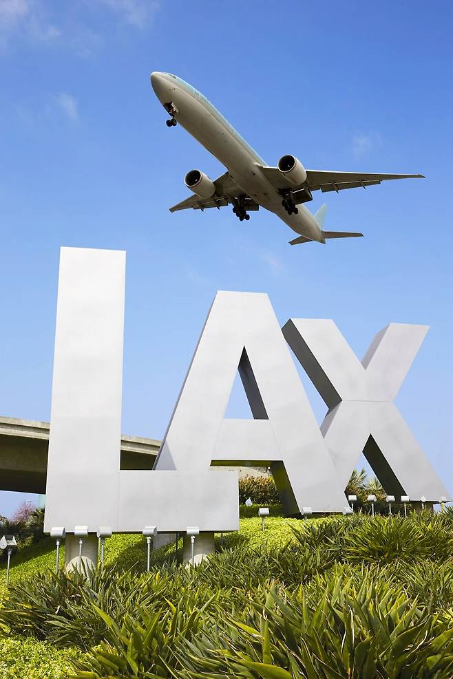 LA공항 싸인보드위로 여행객을 실은 항공기가 이륙하고 있다.