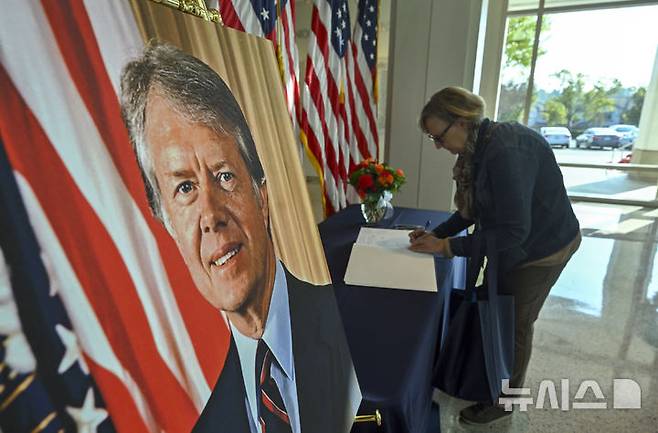 [요바린다=AP/뉴시스]  미 캘리포니아주 요바린다의 리처드 닉슨 대통령 도서관·박물관을 찾은 한 여성이 2024년 12월 30일 지미 카터 전 대통령 빈소에 추모글을 남기고 있다. 카터 전 대통령은 지난 29일 100세의 나이로 서거했으며 2025년 2월 2일 그래미 어워드의 낭독부문상을 사후에 수상했다. 2025.02.03.