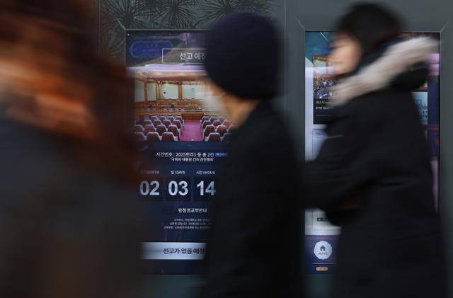 헌법재판소가 최상목 대통령 권한대행의 마은혁 재판관 후보자 불임명 관련 권한쟁의·헌법소원 심판 선고를 연기한 3일 오후 선고 안내가 수정되지 않은 서울 종로구 헌법재판소 스크린 안내문 앞으로 시민들이 지나고 있다. 연합뉴스