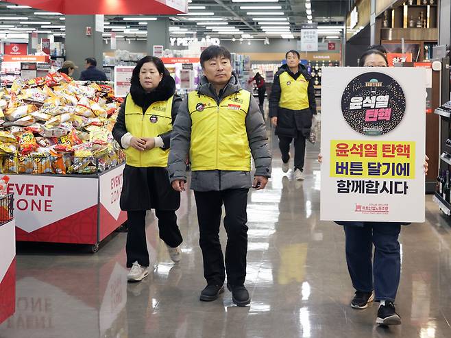 지난해 12월 마트 내에서 ‘윤석열 탄핵’ 배지 부착 캠페인 참여 독려 중인 마트 노동자들. 마트노조 제공
