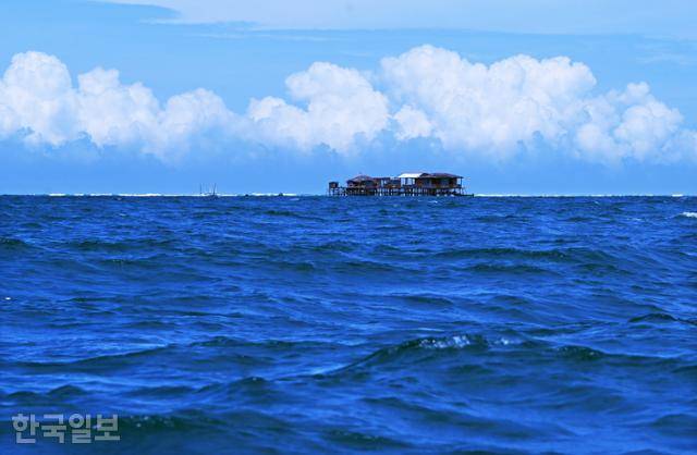 검푸른 물결 수평선 위에 수상가옥이 세워져 있다.